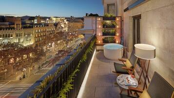 A balcony with a seating area, a hot tub, and a view of the cityscape.
