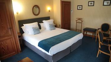 Una habitación de hotel con una cama grande, un armario de madera, un escritorio y una silla.