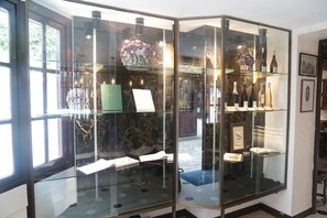Une vitrine en verre contenant des livres, un vase et des bouteilles de vin.
