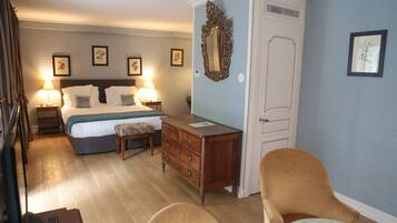 A hotel room with a bed, bedside lamps, a dresser, a chair, and a small table.