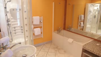Un baño con ducha envuelta en vidrio, bañera blanca, lavamanos y suelo de baldosas.