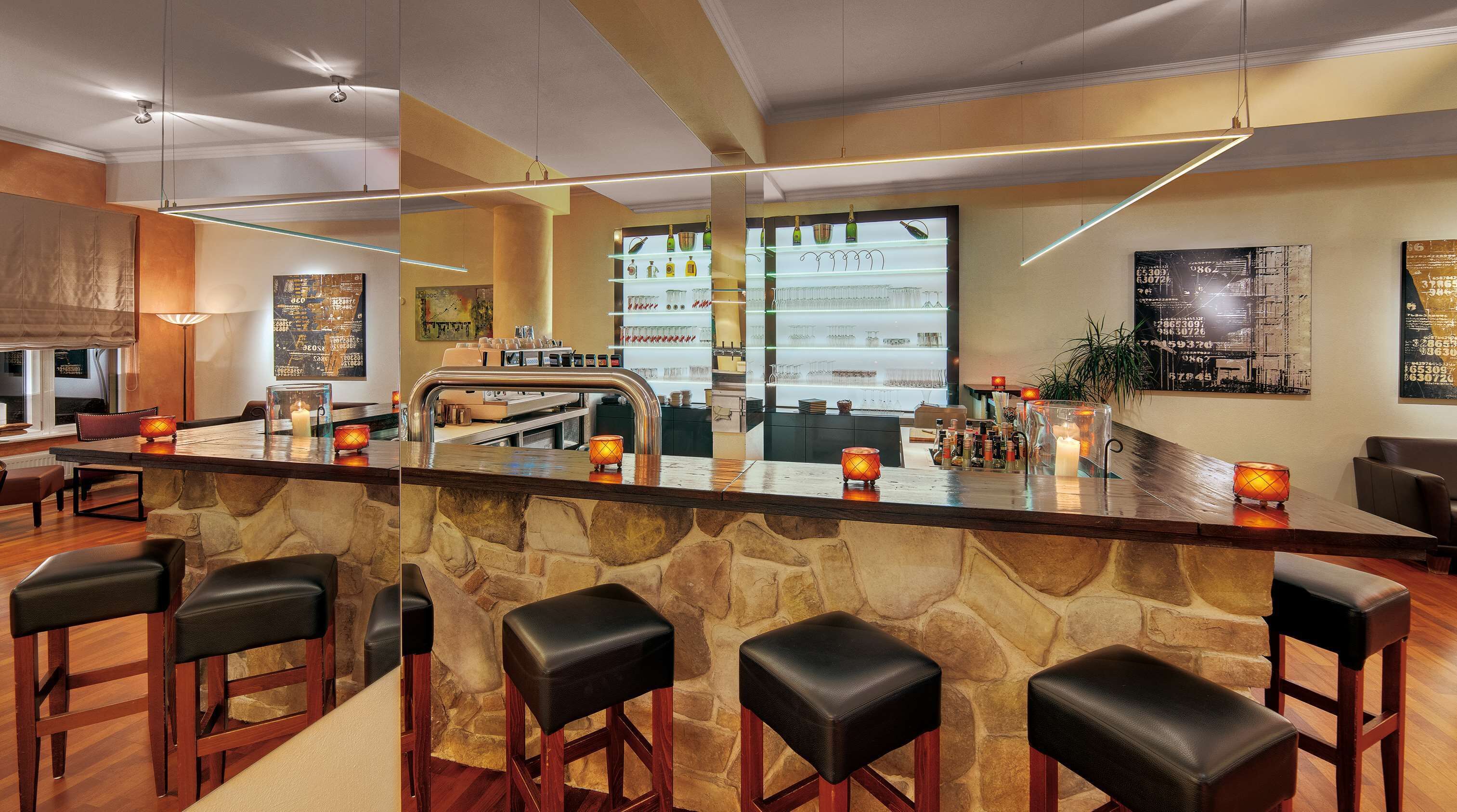 A bar area with a stone counter, bar stools, and a view of the kitchen in the background.