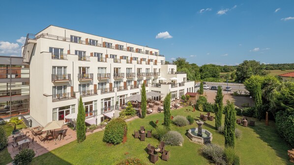A multi-story hotel with outdoor seating and a garden area. - Hotel Villa Medici (Bad Schoenborn)