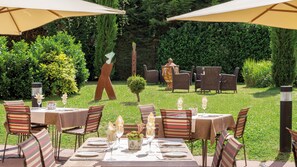 An outdoor dining area with tables and chairs, surrounded by greenery and a hedge. - Hotel Villa Medici (Bad Schoenborn)
