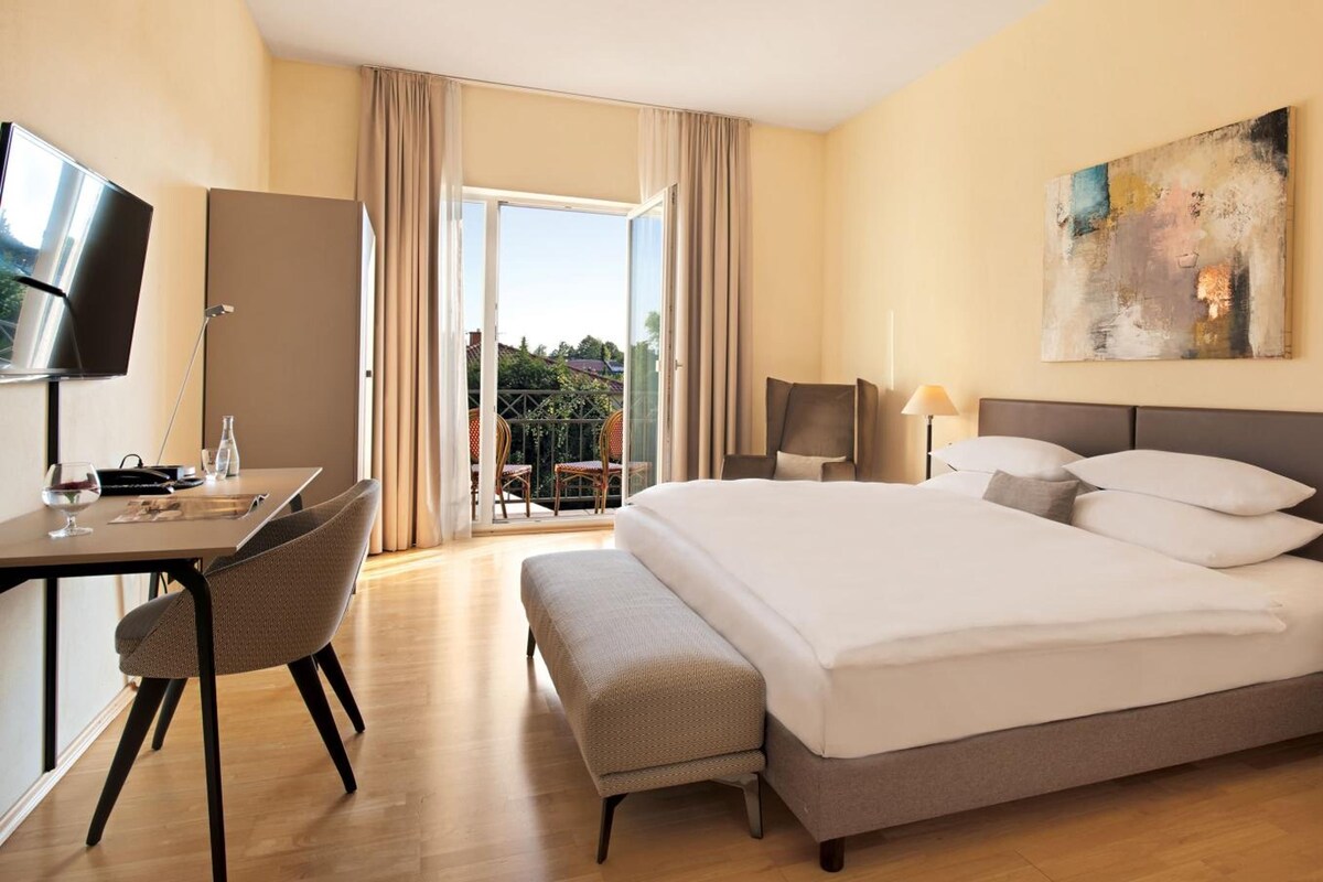 Hotelkamer met een bed, bureau, stoel, televisie en een schilderij aan de muur.