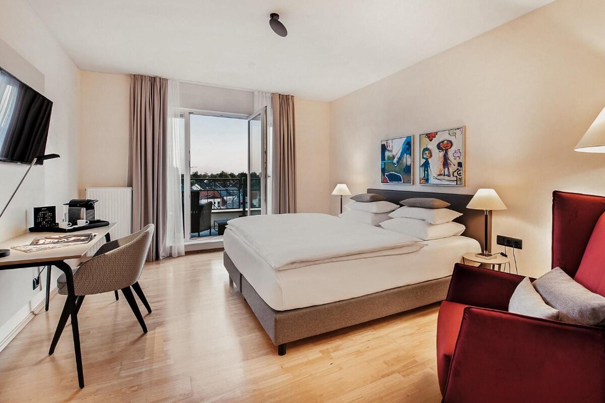 Een hotelkamer met een bed, een bureau met stoel, een televisie en kunst aan de muur.