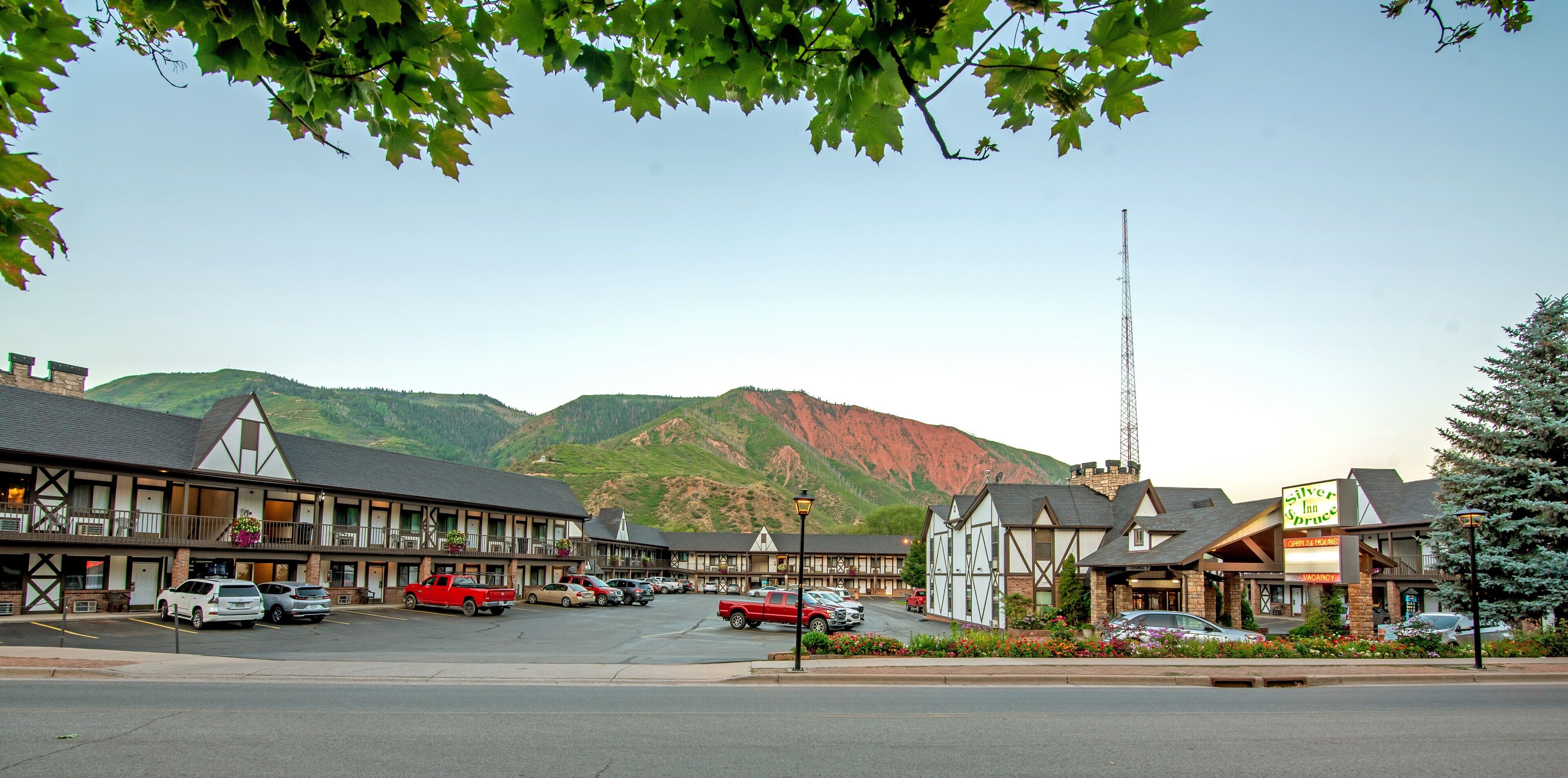 Ett hotell i traditionell europeisk arkitektonisk stil, med en central innergård med en fontän, omgiven av en parkeringsplats med flera bilar.