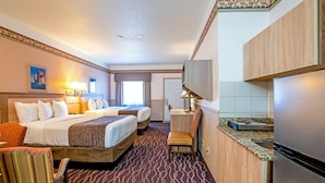 A hotel room with two beds, a desk, a chair, a kitchenette, and a bathroom. - Silver Spruce Inn (Glenwood Springs)