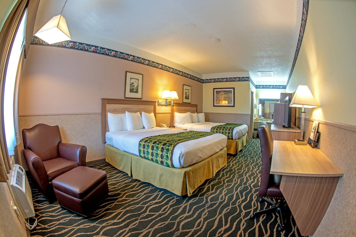 A hotel room with two beds, a desk, a chair, and a massage chair.