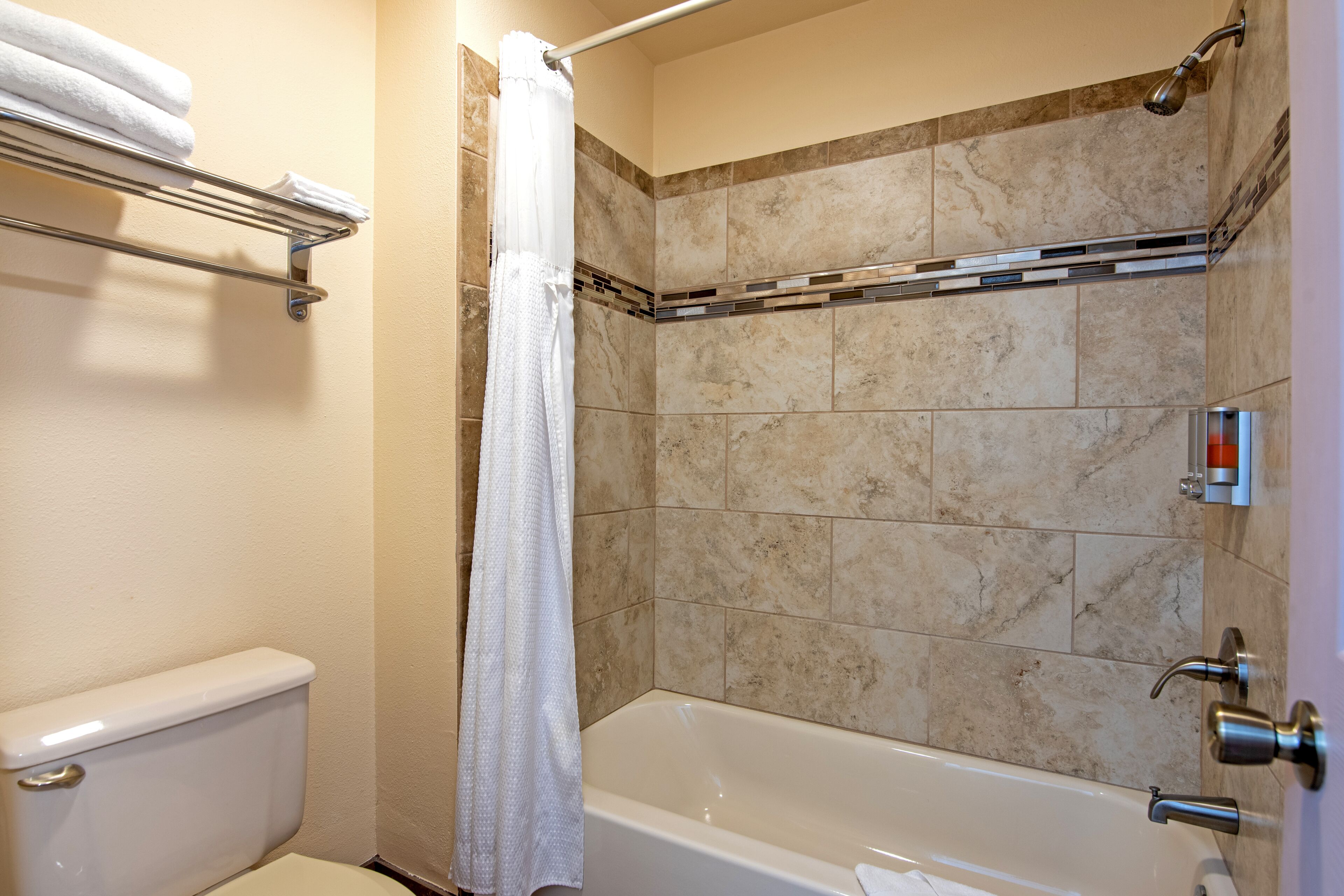 Een badkamer met een bad, toilet, handdoekhouder en douchegordijn.