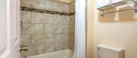 A bathroom with a bathtub, shower, toilet, and towel rack.