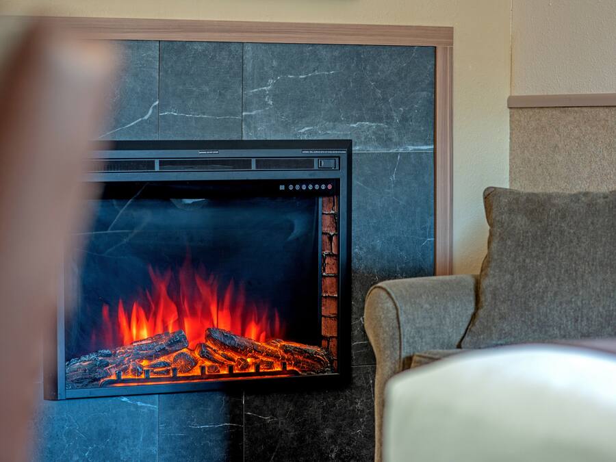 A modern fireplace with a digital display, set against a dark marble wall.