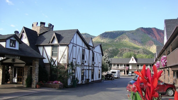 A traditional half-timbered building with a stone facade, a clear sky, and a mountainous backdrop. - Silver Spruce Inn (Glenwood Springs)