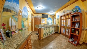 A kitchen with a granite countertop, wooden cabinets, and a mural of a landscape on the wall. - Silver Spruce Inn (Glenwood Springs)