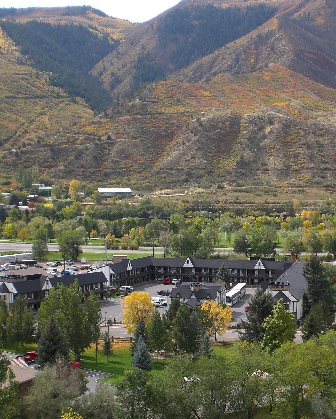A hotel with a central courtyard, surrounded by trees and a mountainous backdrop.