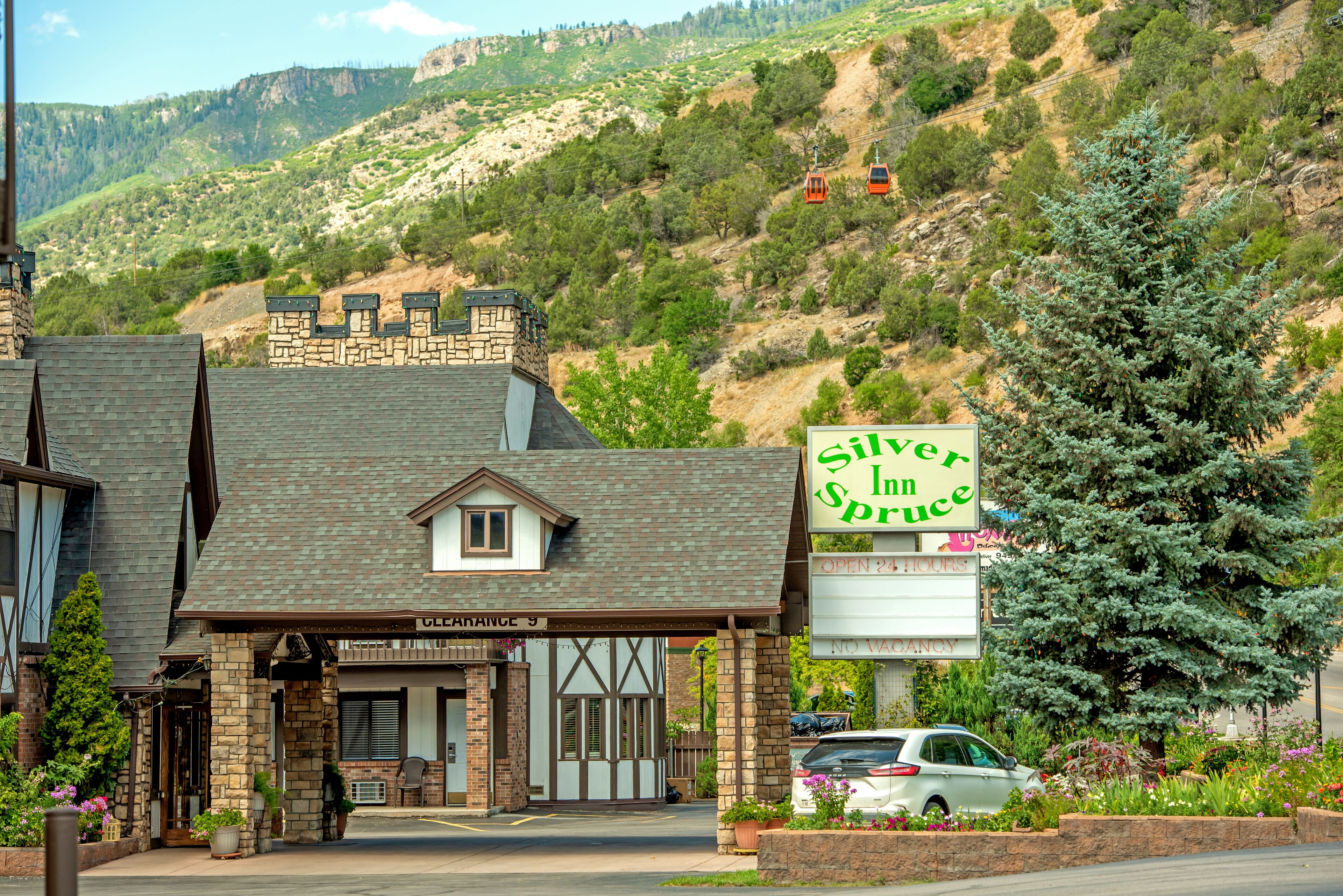A hotel with a stone facade, a sign for 'Silver Inn in Bruce', and a view of a mountainous landscape.
