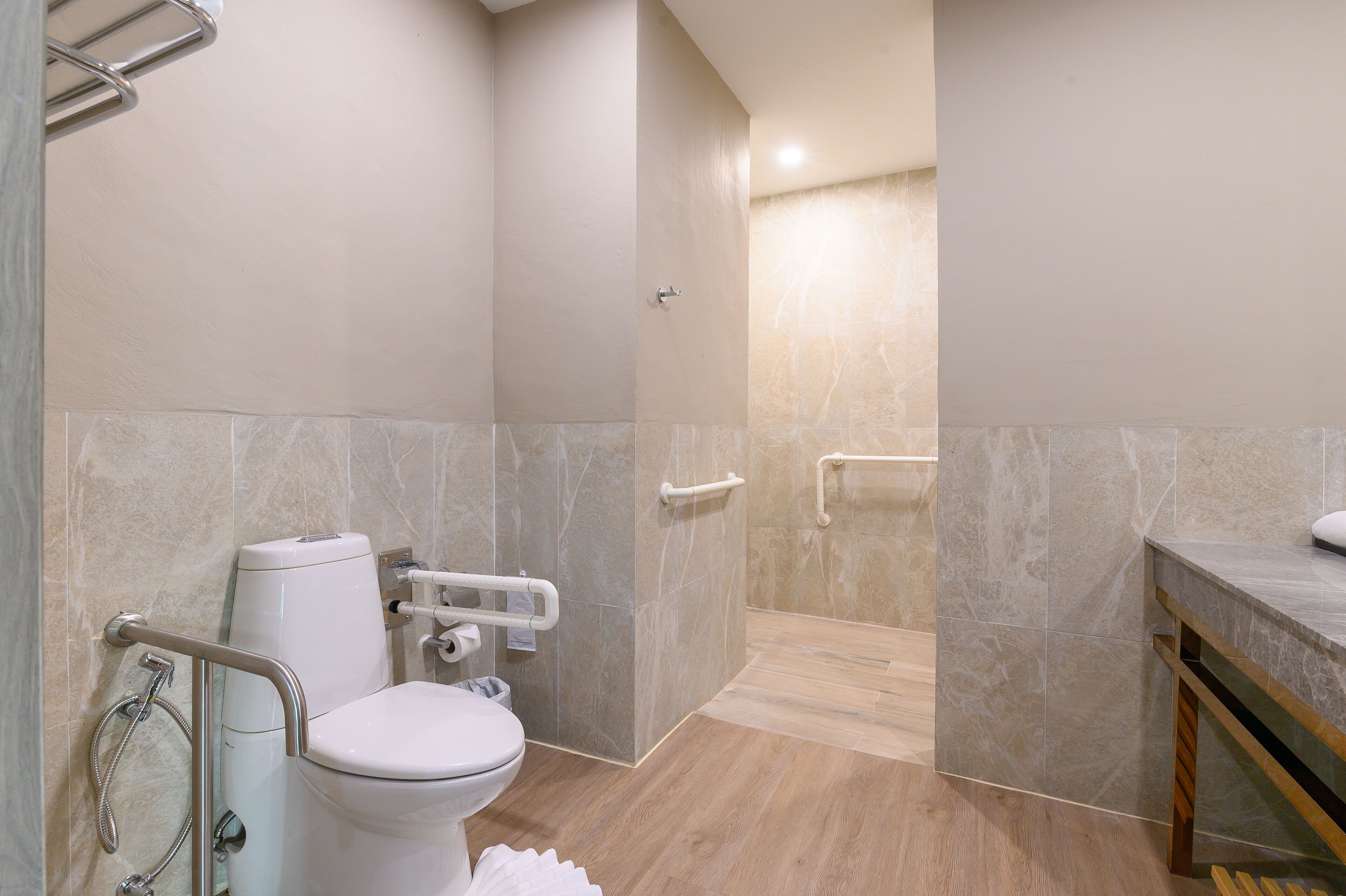 Un baño moderno con inodoro, ducha y barras de apoyo.