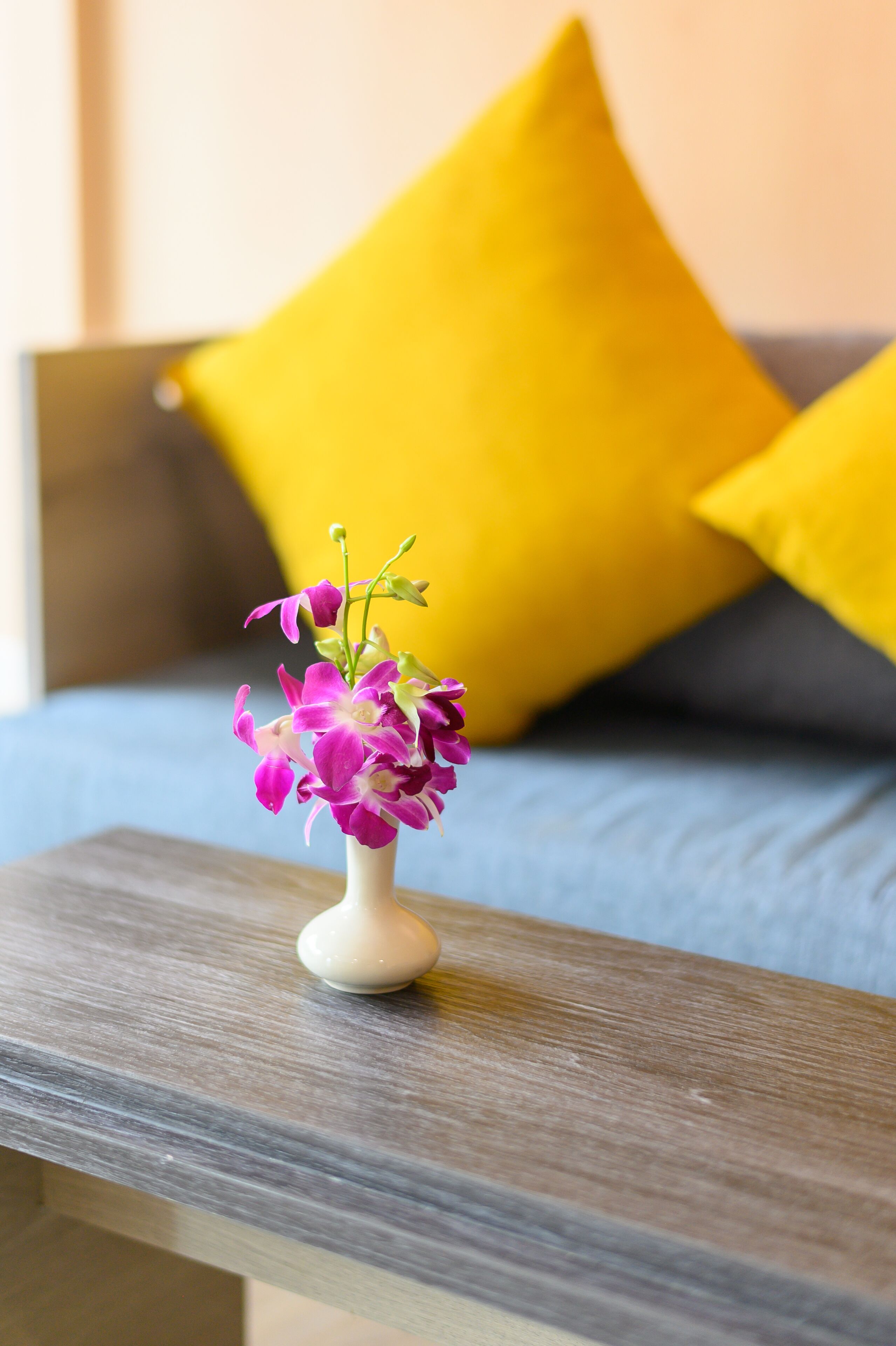 Eine kleine weiße Vase mit rosa und violetten Blumen auf einem Holztisch.