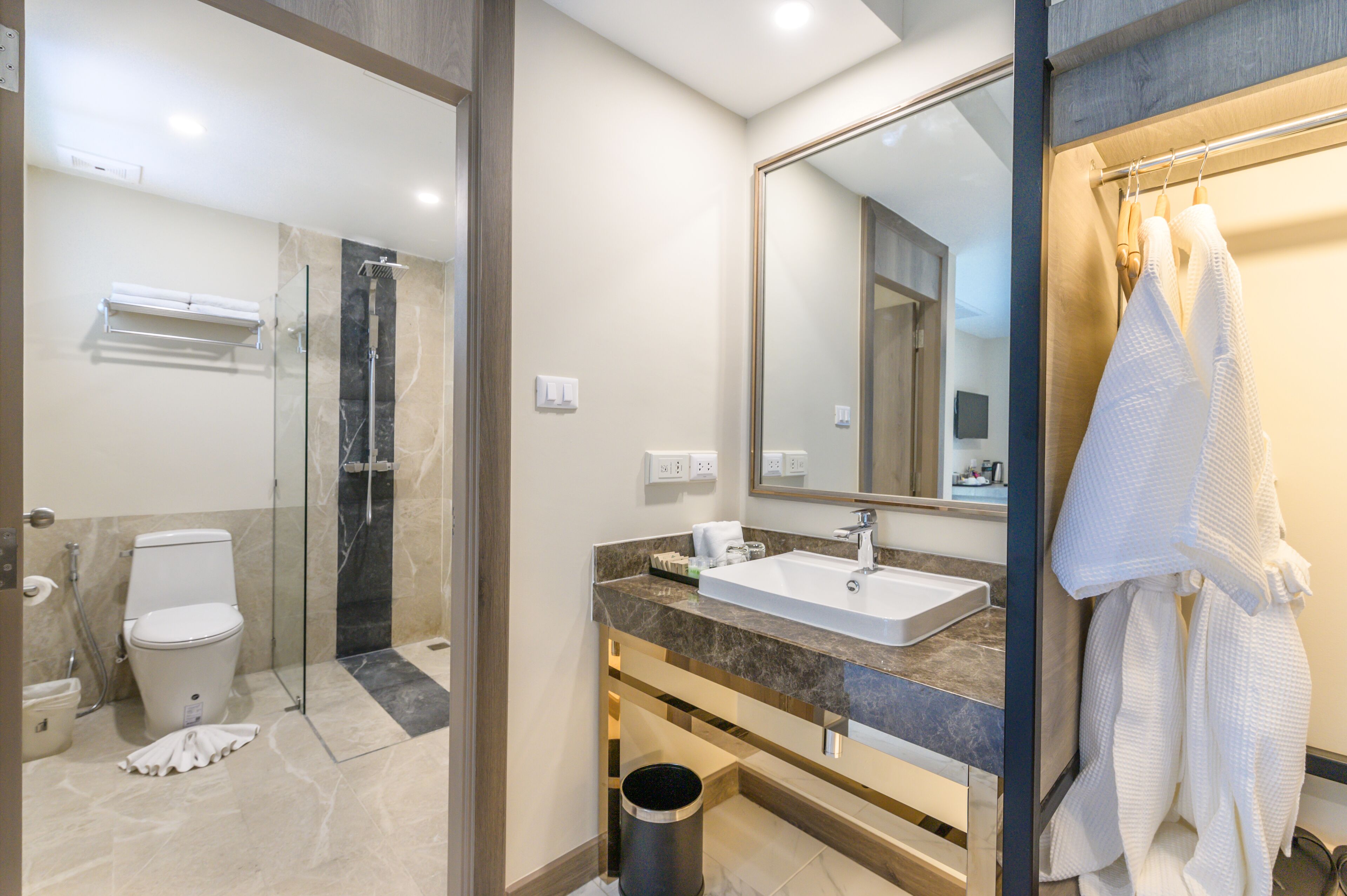 A modern bathroom with a glass-enclosed shower, a white sink, and a large mirror.