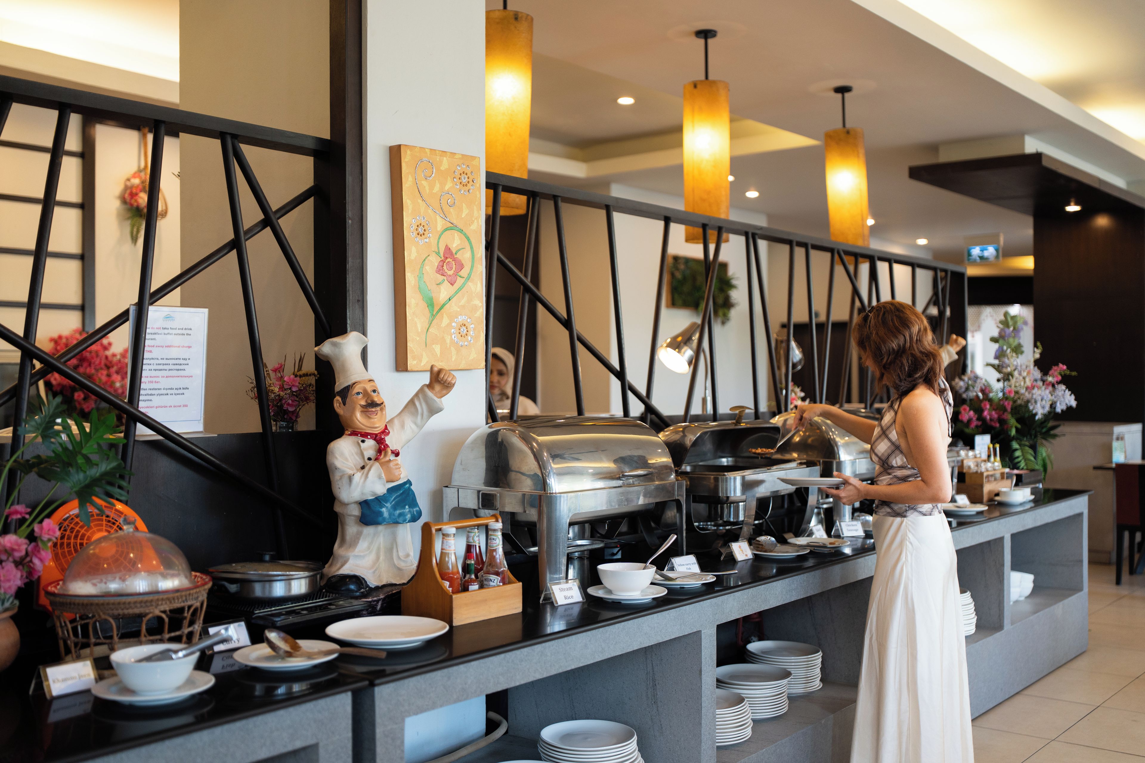 A buffet setup with a variety of food items and a staff member serving.