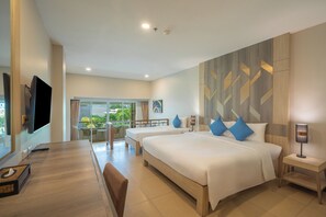 Habitación de hotel con una cama grande, un escritorio, televisión y un balcón con vistas a zonas verdes.