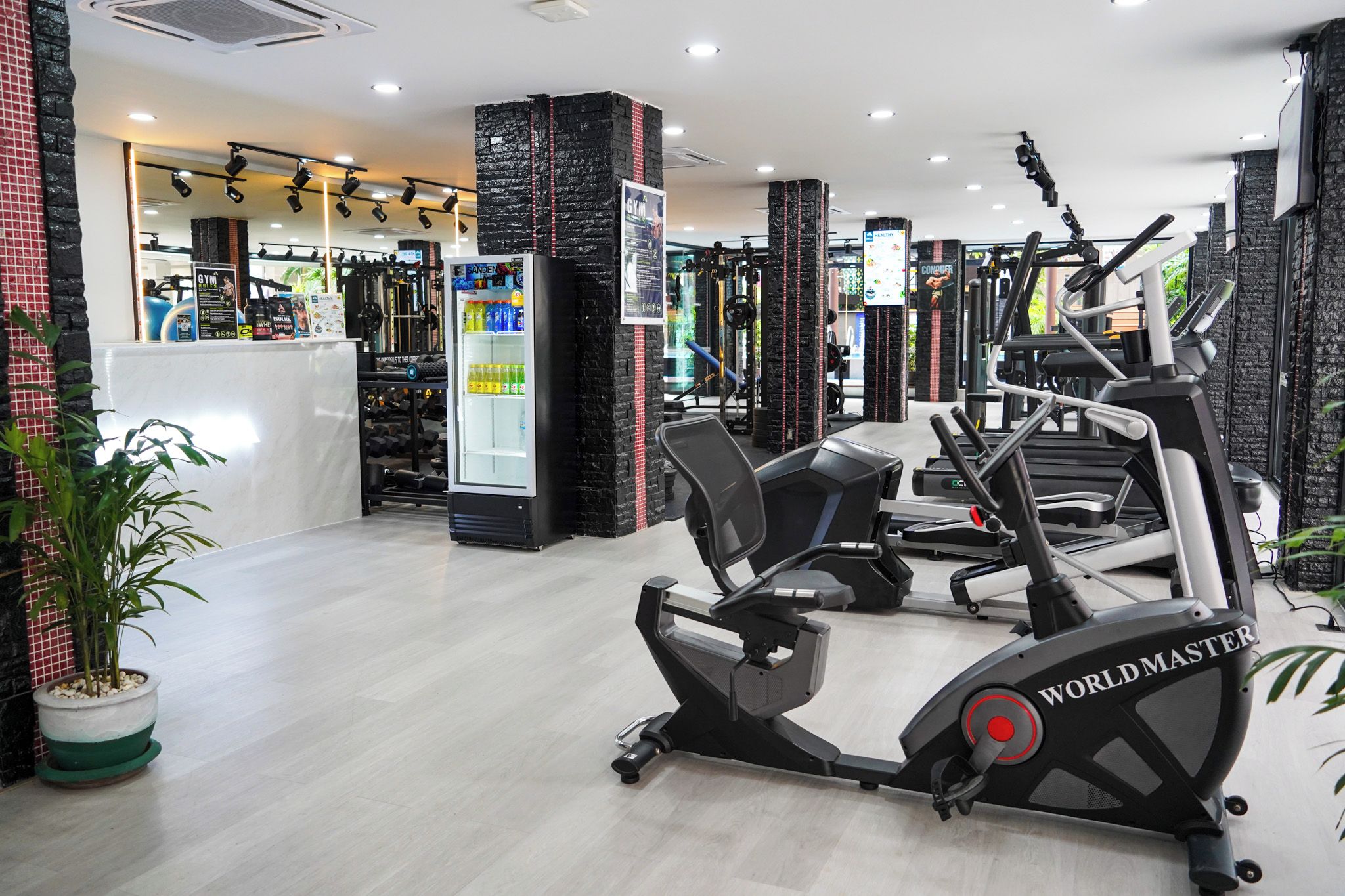 A gym with treadmills, weight machines, and a juice cooler.