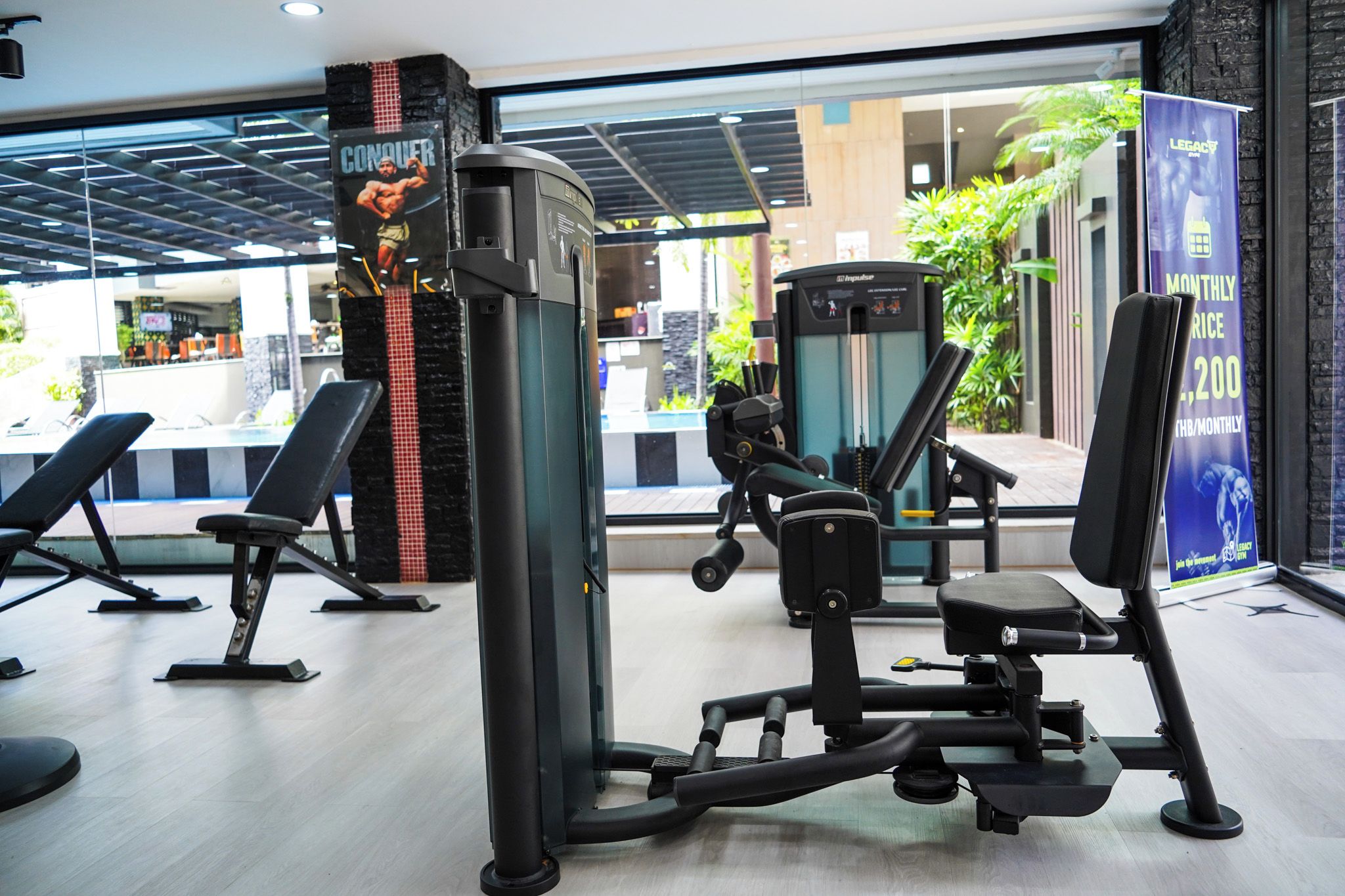 Un gimnasio con equipo de ejercicio, bancos y vistas al exterior.