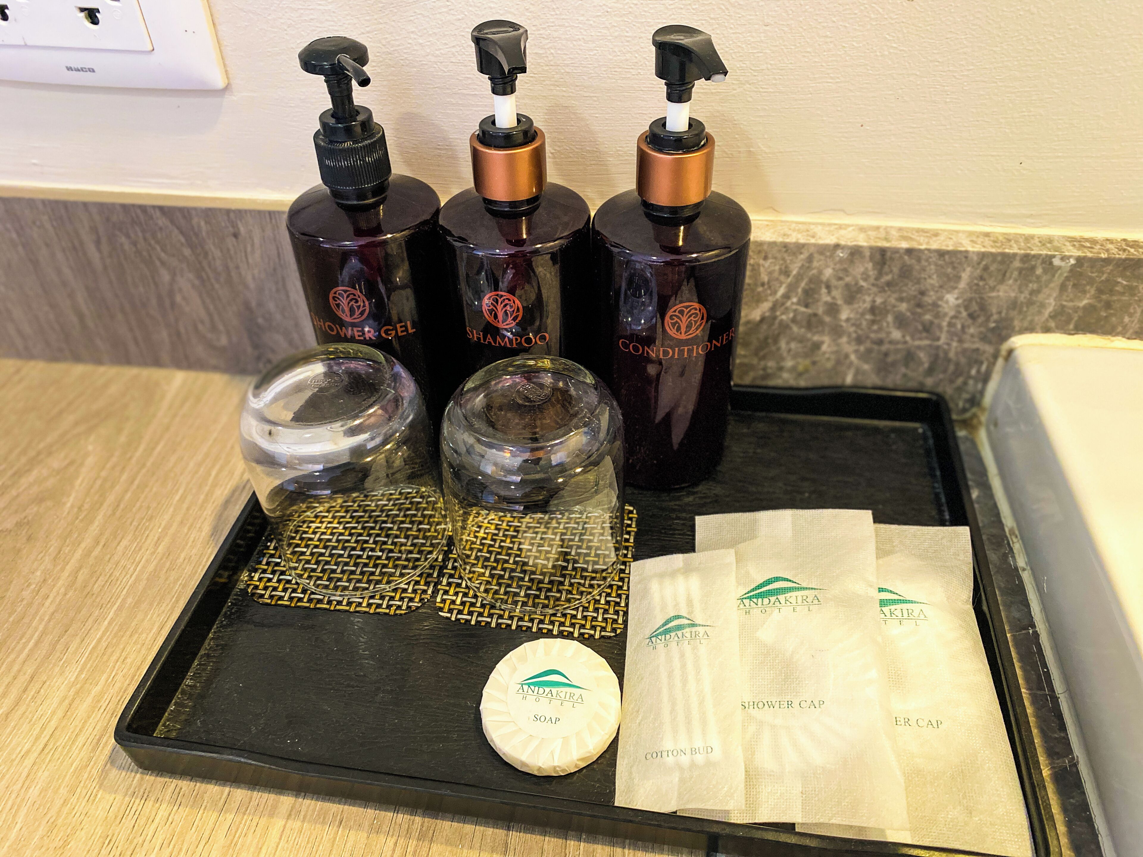 A bathroom counter with toiletries including shower gel, shampoo, conditioner, and soap.