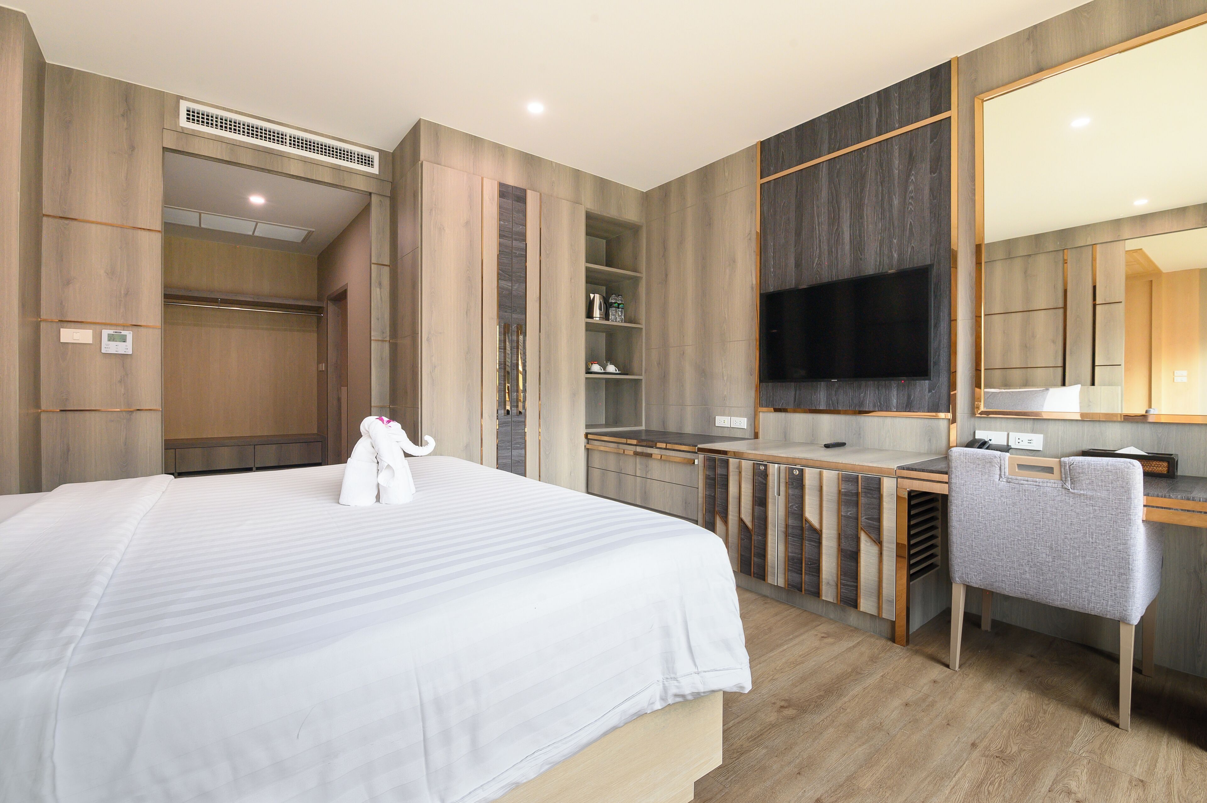 Een moderne hotelkamer met een groot bed, een bureau, een stoel, een televisie en een kledingkast.
