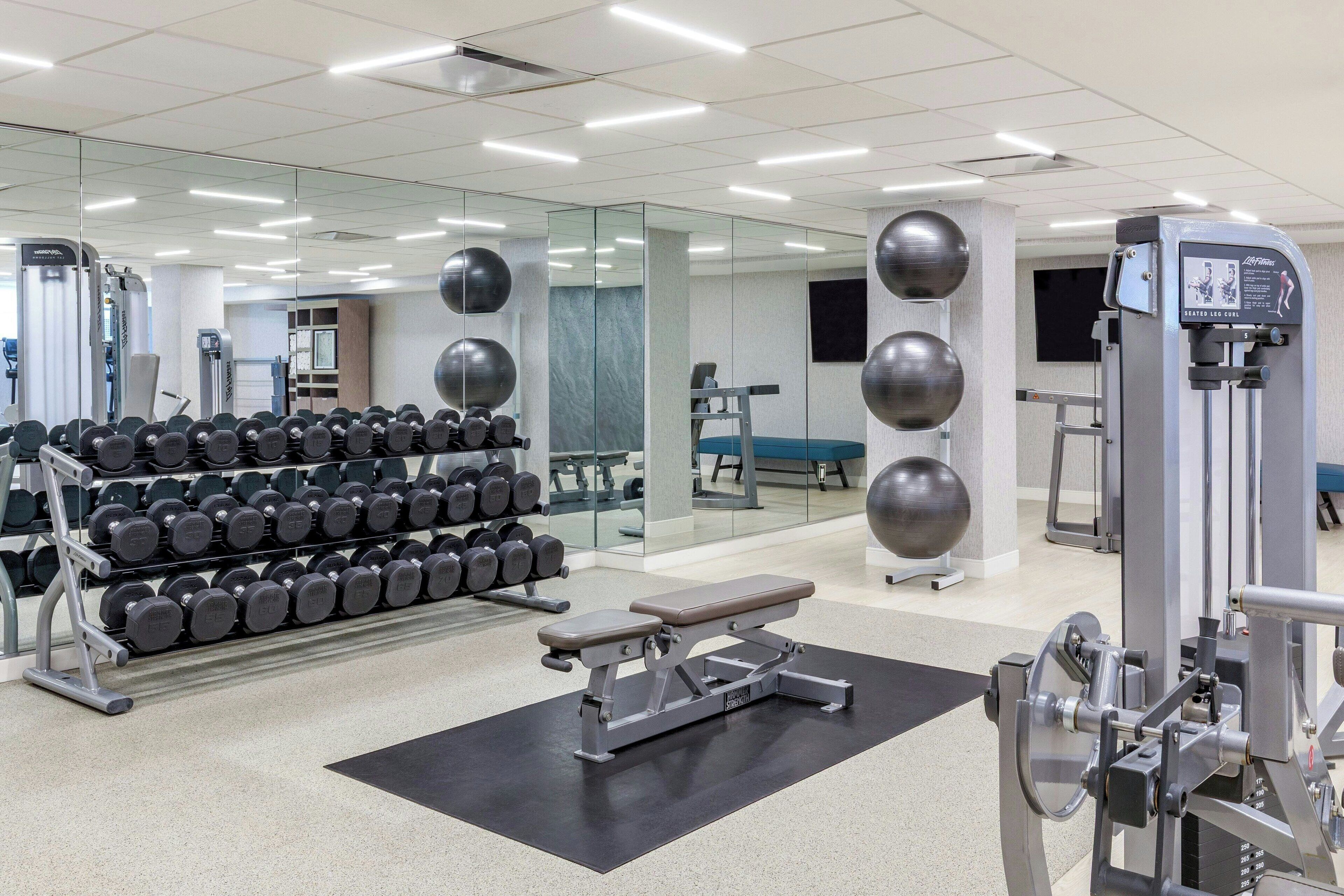 A gym with weightlifting equipment, dumbbells, and exercise machines.