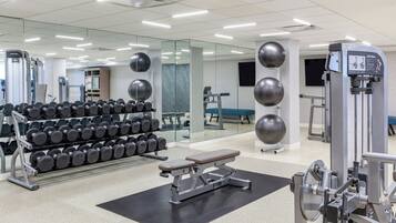 A gym with weightlifting equipment, dumbbells, and exercise machines.
