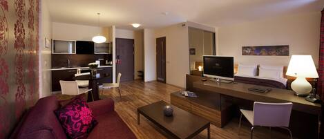Una habitación de hotel moderna con zona de estar, kitchenette y cama.