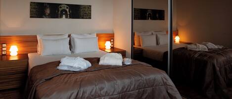 A hotel room with a large bed, two bedside tables with lamps, a mirror, and artwork on the wall.