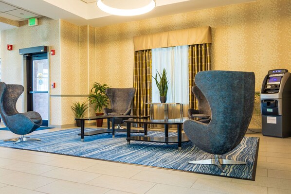 Welcome to our lobby, featuring a comfortable reception area with a round table and armchairs, a large window, and a potted plant.
