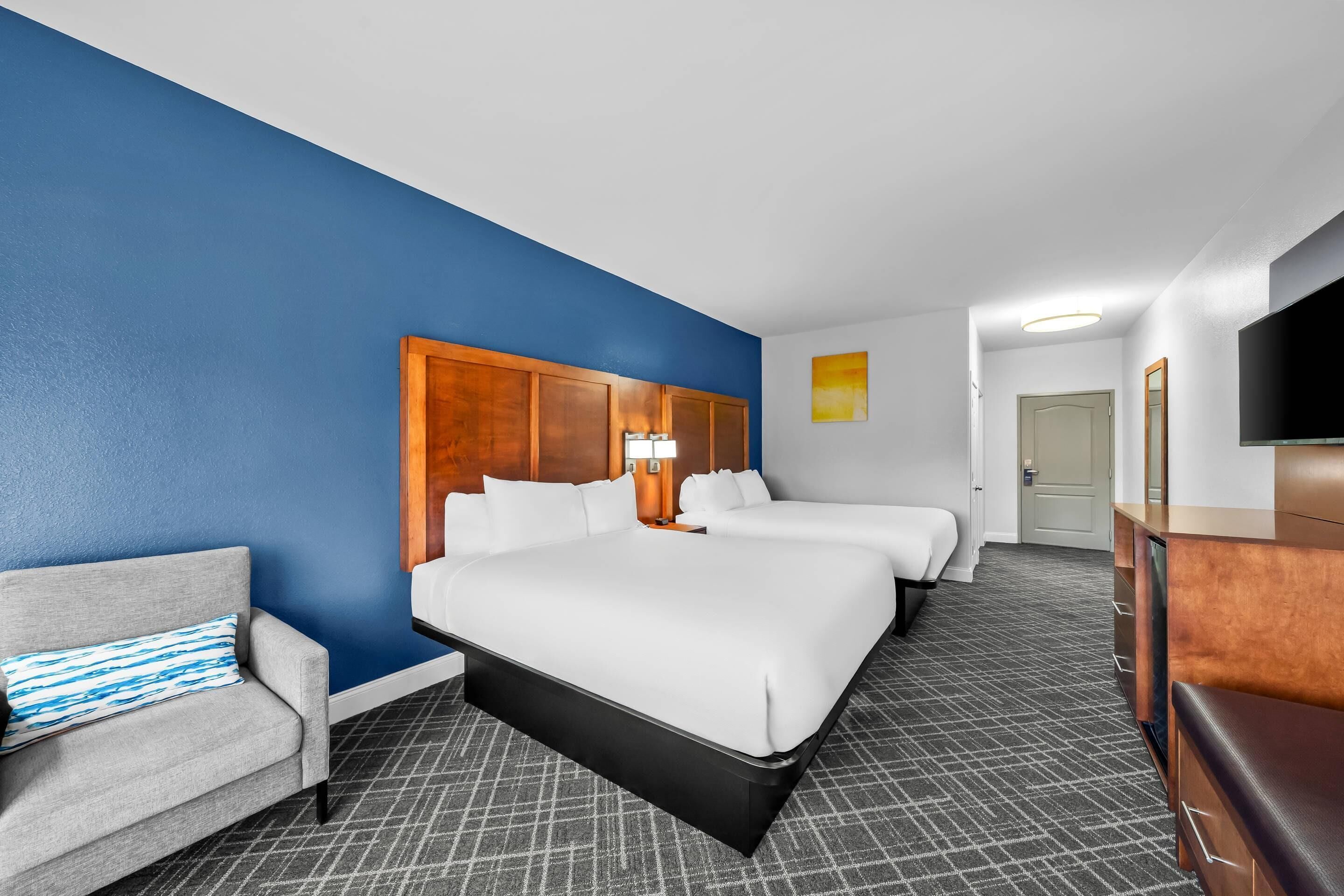 Een hotelkamer met een groot bed, een kleiner bed, een bank, een bureau en een televisie.
