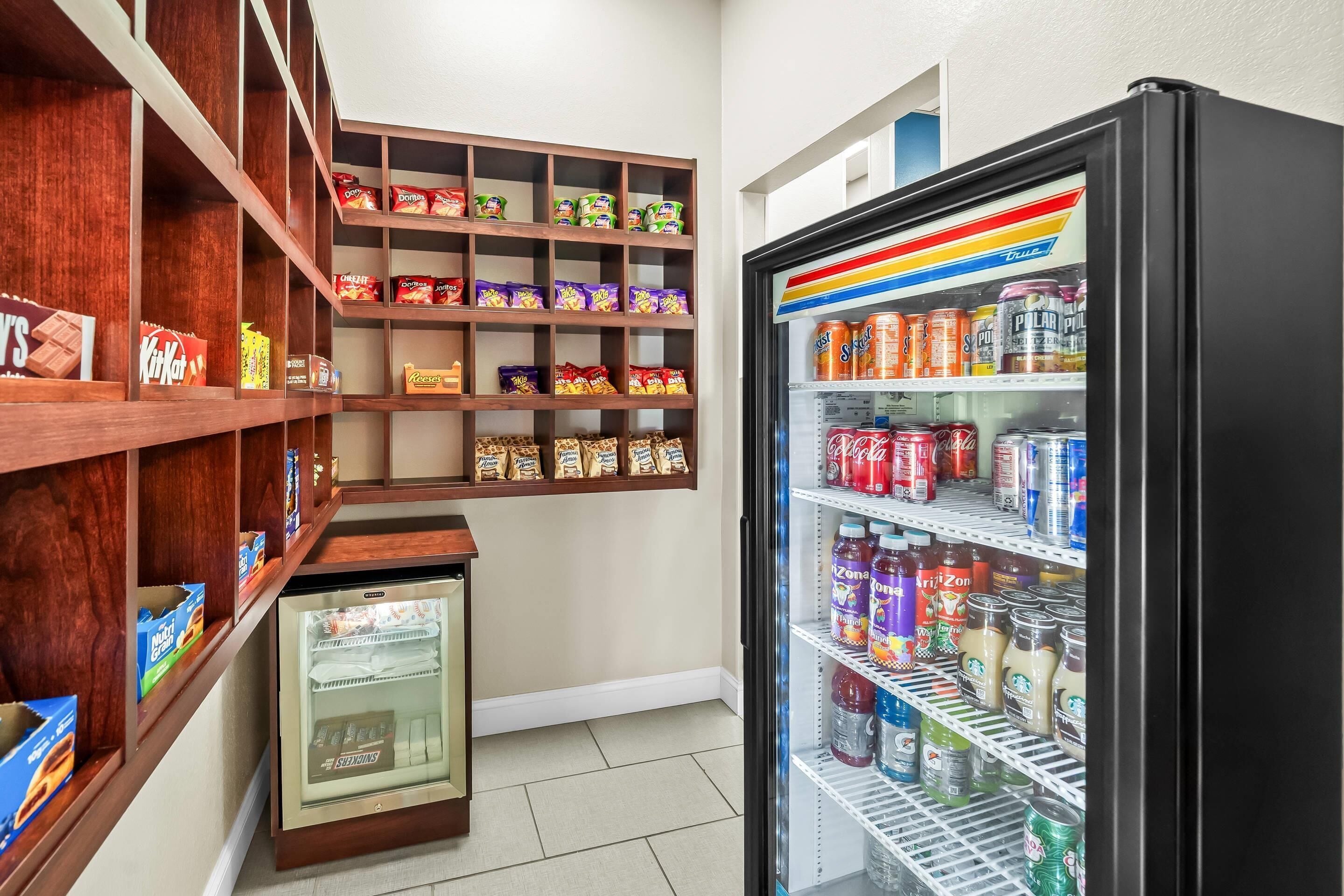 A vending machine stocked with snacks and drinks, a refrigerated display case, and shelves with packaged goods.