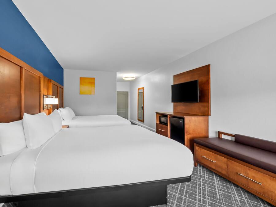 Ein Hotelzimmer mit einem großen Bett, einem Schreibtisch, einem Fernseher und einer Sitzbank.