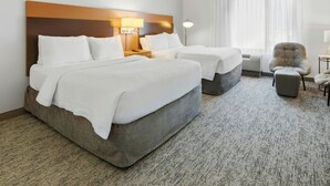A hotel room with two beds, a chair, a lamp, and a window with curtains. - TownePlace Suites by Marriott Farmington (Farmington)