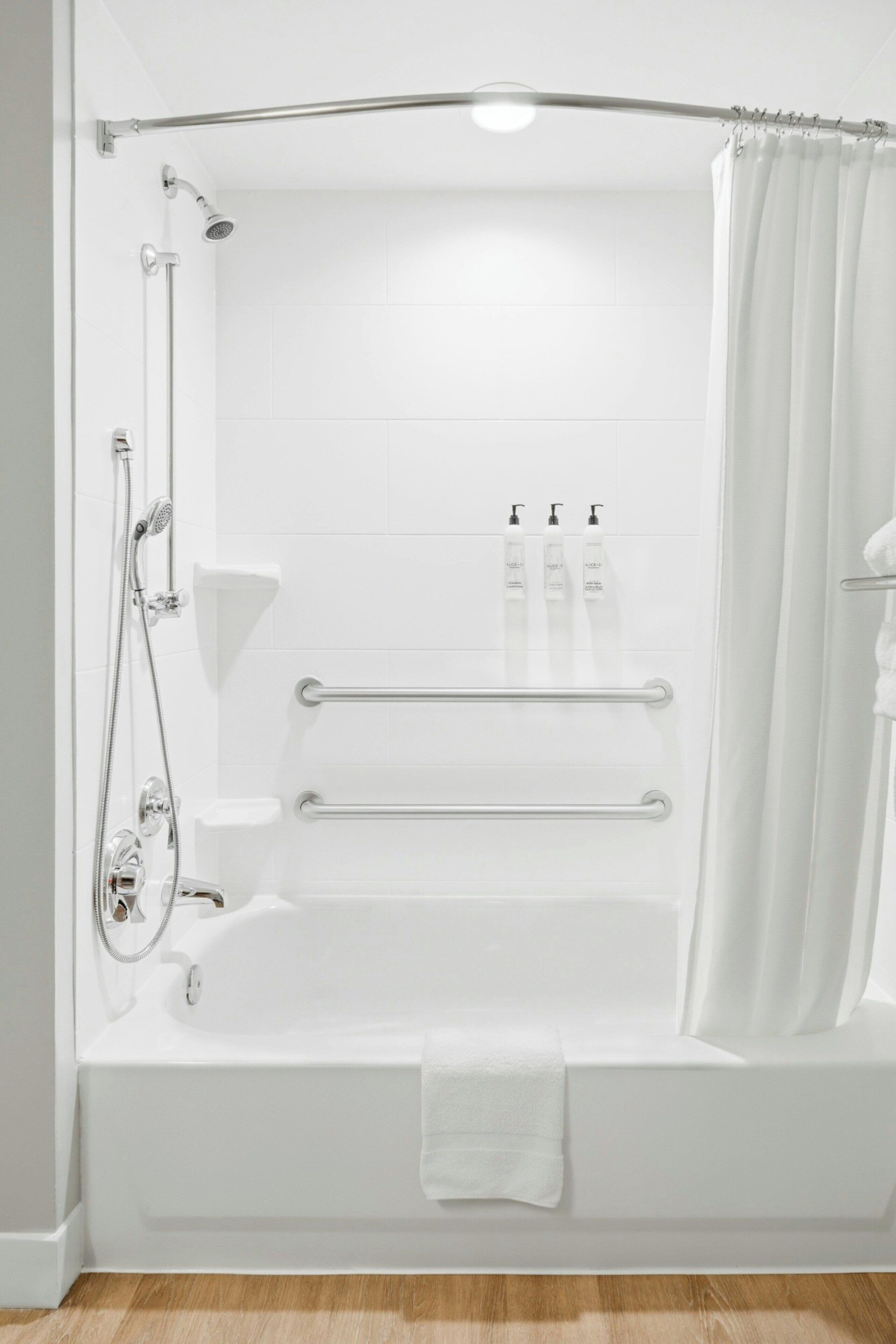 Een moderne badkamer met een badkuip, douche en handgrepen.