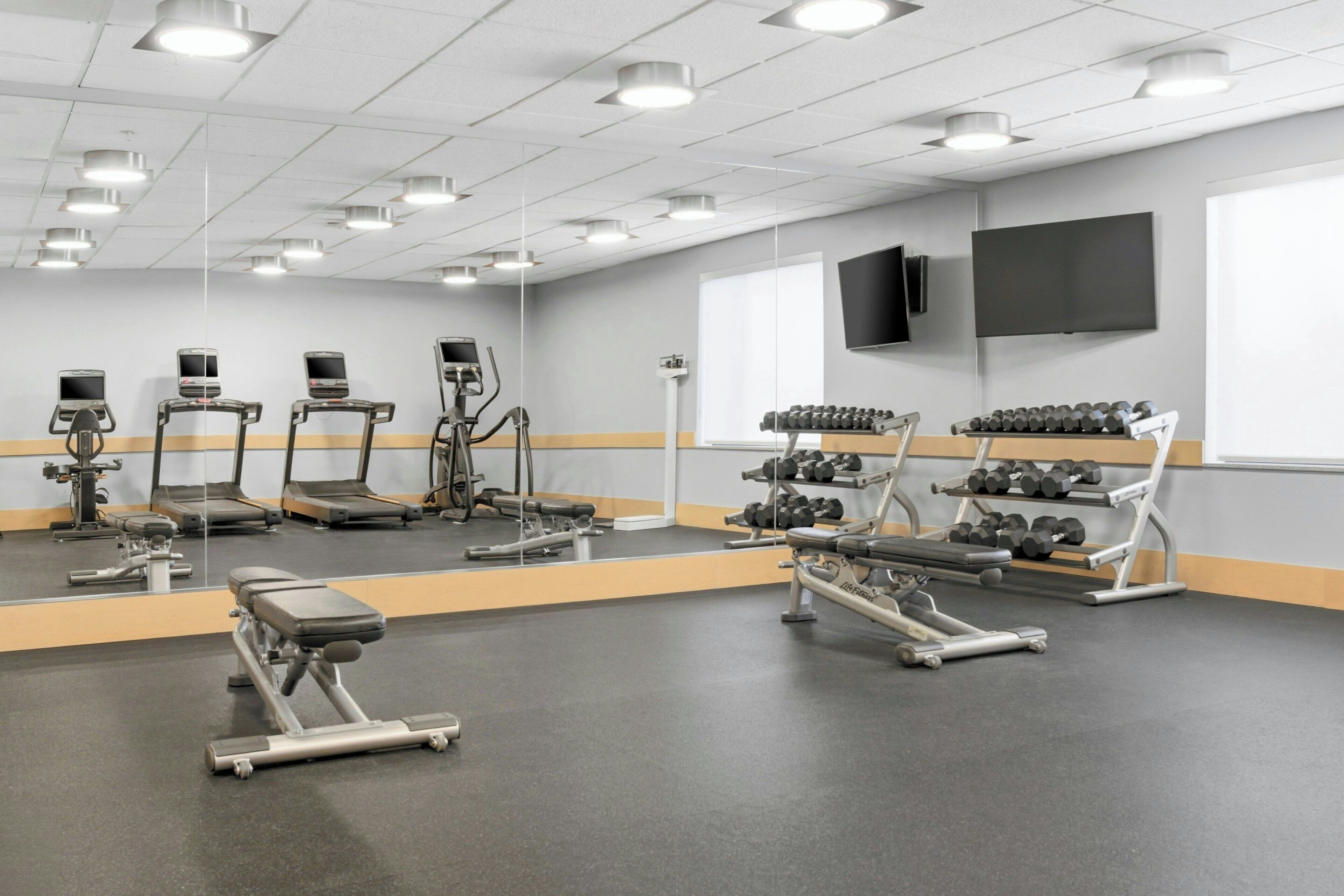 A gym with treadmills, elliptical machines, and free weights.