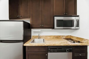 A kitchen with a stainless steel refrigerator, a microwave, a sink, and a dishwasher.