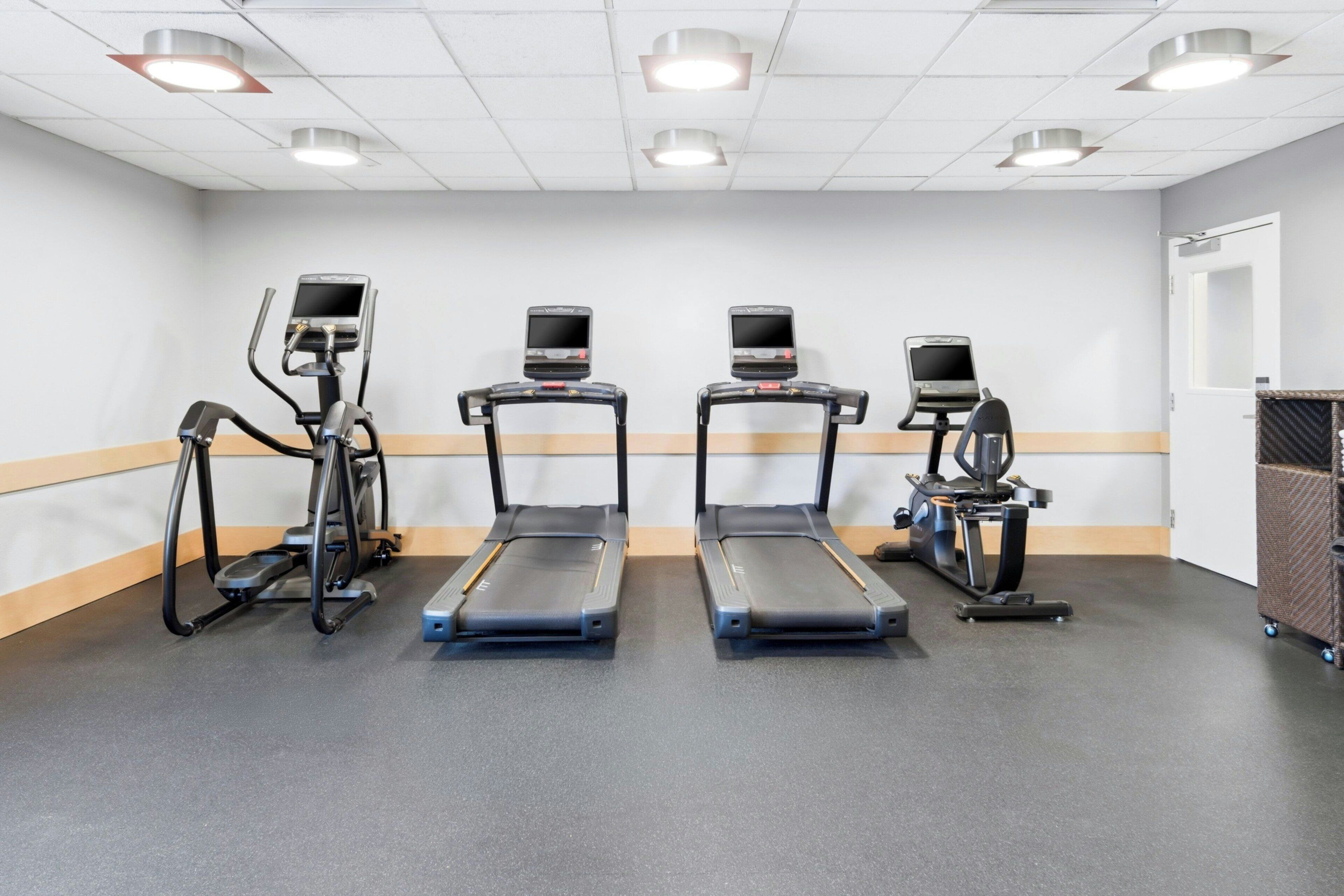 Ein Fitnessraum mit Laufbändern, einem Ergometer und einem Rudergerät.