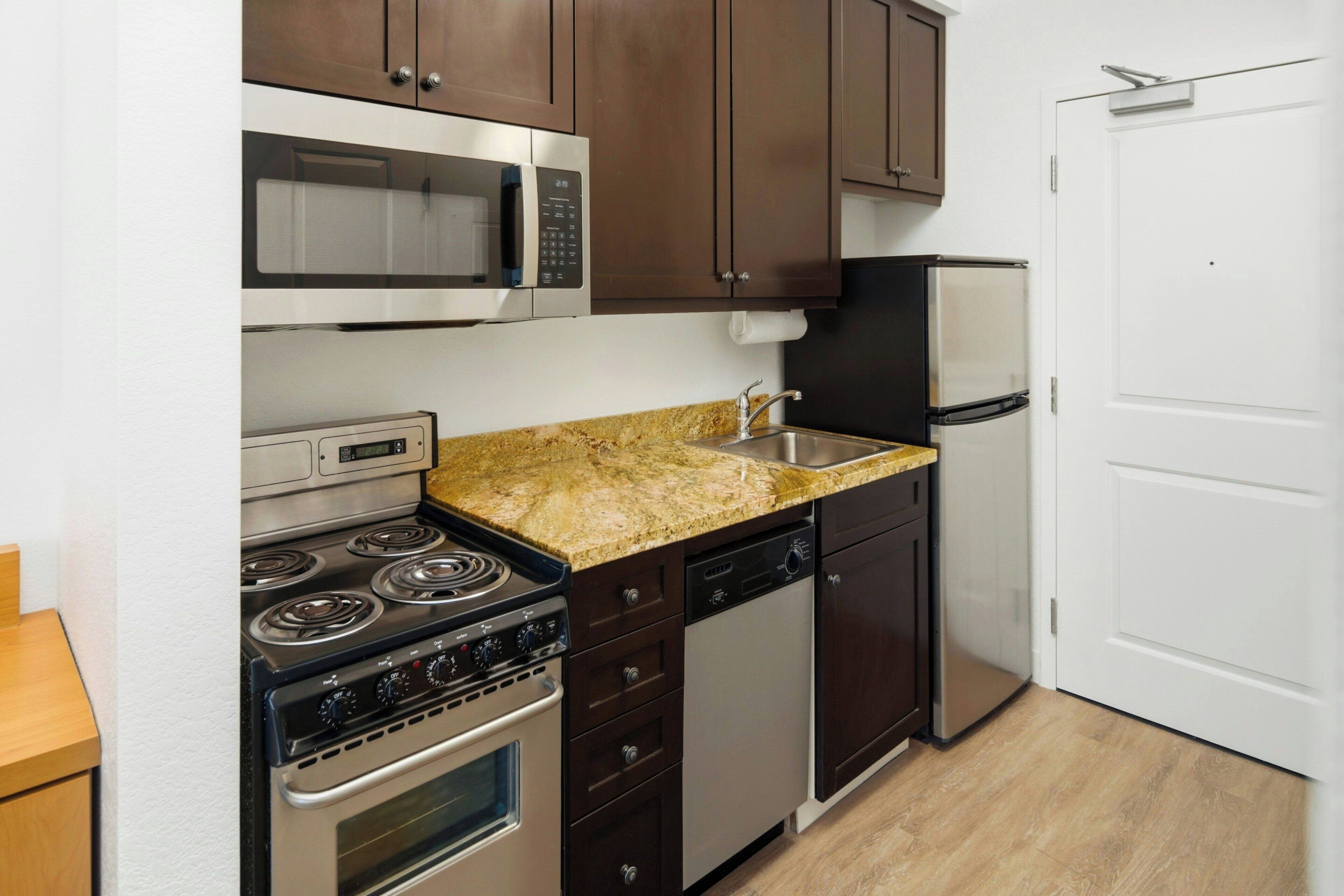 Una cocina equipada con estufa, microondas, refrigerador, lavavajillas y encimera de granito.
