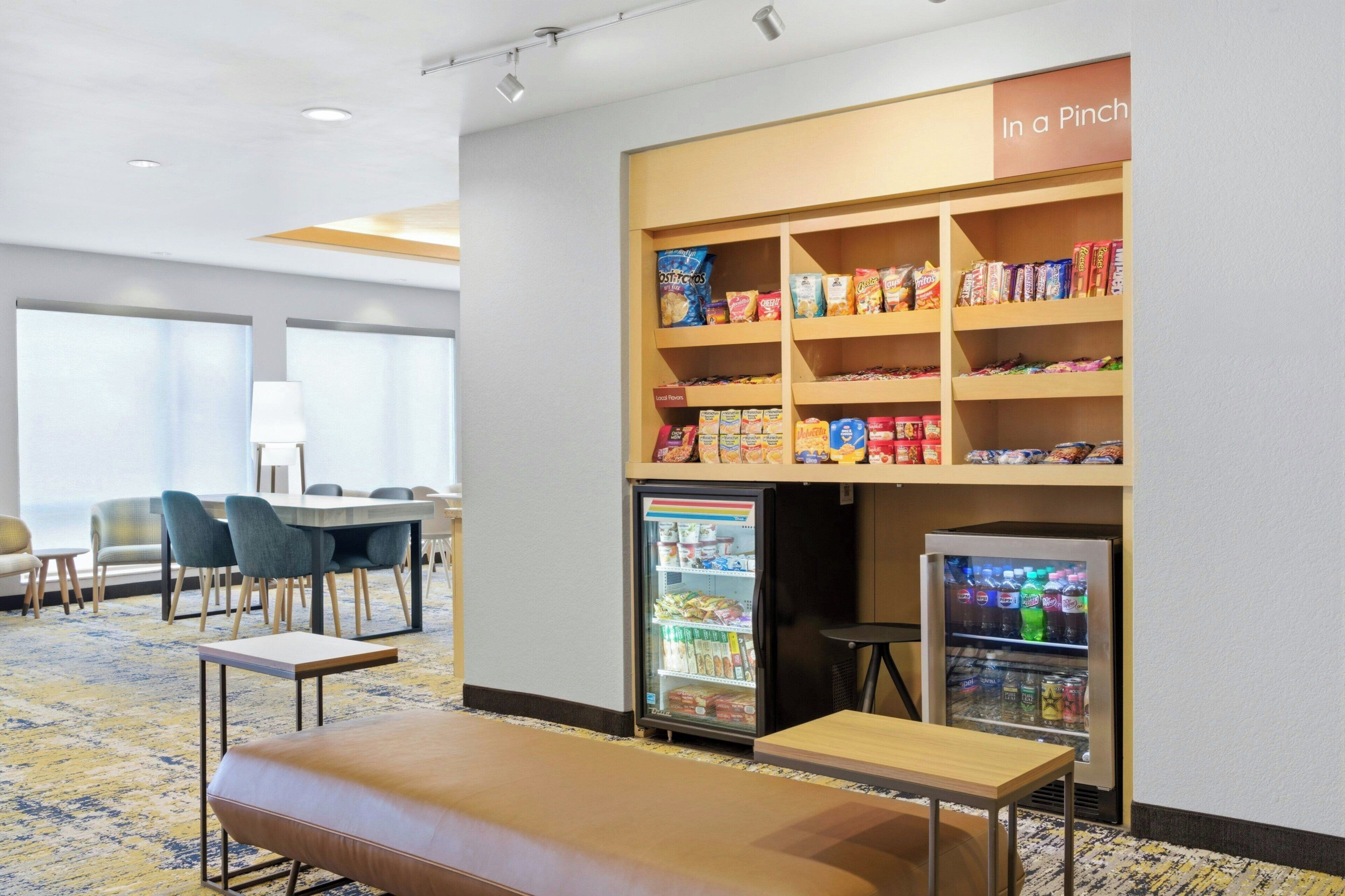 A hotel room with a seating area, a snack bar, and a refrigerator.