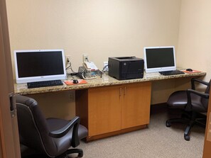 A workspace with two desktop computers, a printer, and office chairs.