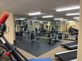 Un gimnasio con equipo de ejercicio, espejos y una cinta de correr.