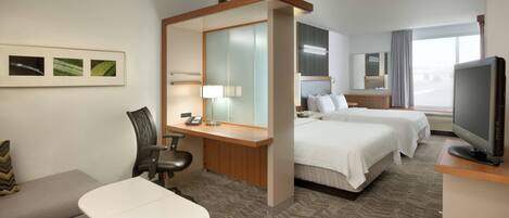 Une chambre d’hôtel comprenant un lit, un bureau avec une chaise, un petit canapé, une télévision et une fenêtre.