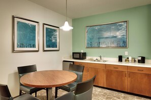 A dining area with a round wooden table, four chairs, a microwave, a sink, and cabinets. - SpringHill Suites by Marriott Rexburg (Rexburg)