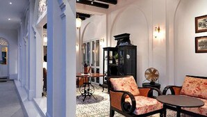A spacious lobby with a high ceiling, a central seating area with a table and chairs, and a decorative fireplace.