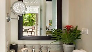 A bathroom with a large mirror, a sink, and a potted plant.